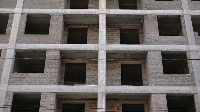 Multi-storey residential building under construction. Closeup view, camera moving up.