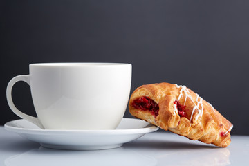 Afternoon tea and croissant on serving table over dark grey background, close-up, selective focus