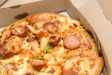 Close up of pizzas with variety of toppings and cheese in cardboard take out boxes with open lid