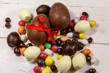 Easter composition with chocolate eggs on white wooden background
