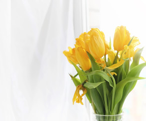 A bouquet of red tulips in a vase on the windowsill. A gift for 
