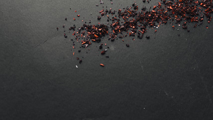 Fototapeta na wymiar Scattered red spice on black background