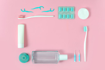 Toothbrushes, toothpaste, rinse and chewing gum set in shape of frame on pink background. Dental...