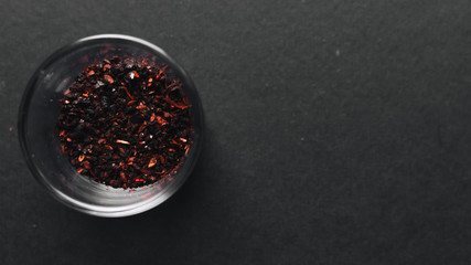 Glass with red spice on black background