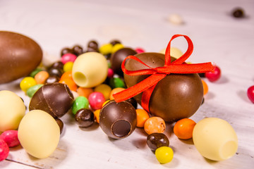 Chocolate easter eggs and multicolored candies on wooden table