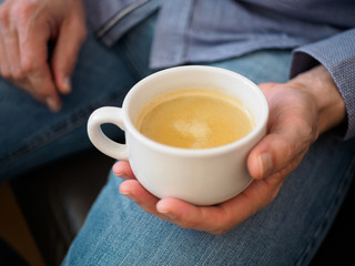 Hand hält eine Tasse Kaffee