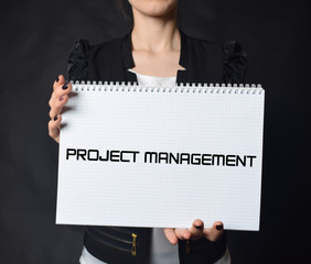 In the hands of a businessman a notebook with the inscription:PROJECT MANAGEMENT