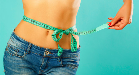 Woman measuring her waist over white background. Wellness concept
