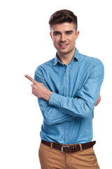 smiling casual man with hands crossed is pointing to side