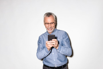 Happy old man in blue shirt using smartphone isolated