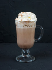 A glass with whipped cream on black background.