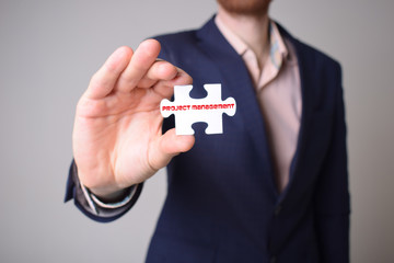 Businessman holding a puzzle with the inscription:PROJECT MANAGEMENT