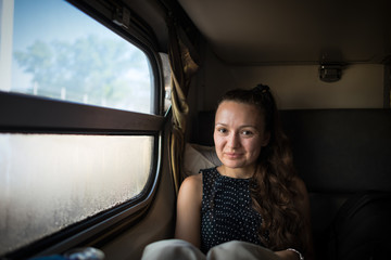 Traveling to new destination by the train. Beautiful young woman sits near the window in the compartment in train. Attractive female traveler just wake up at the train