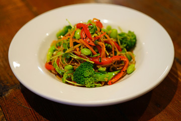 Plate of vegetable soba noodle stir fry with peppers, broccoli and edamame