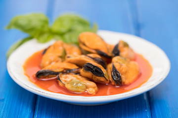 mussels in sauce on white dish on wooden background