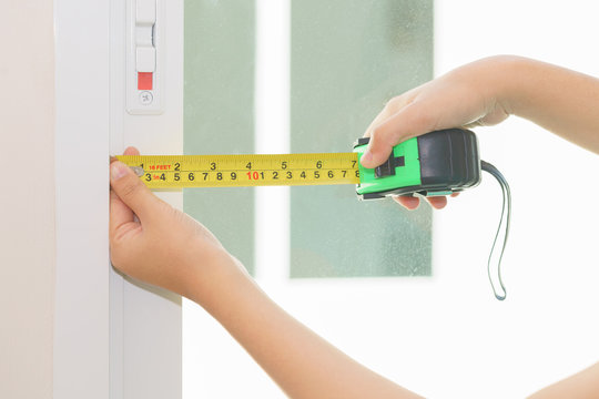 Close up of handyman hands using tape ruler with white window