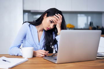 Tired woman working with laptop in home office