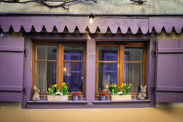 Art window with purple wooden shutters and flower pots with flowers, design element and toys, vintage decor