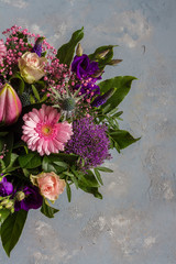 Purple and pink flowers bouquet. Glass vase. Gray backround.