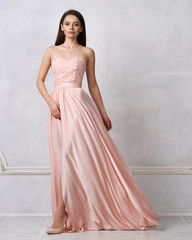 Full body portrait of gorgeous young brunette woman dressed in exquisite nude ball gown with lace...