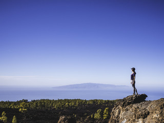 Woman on top of a cliff looking afar in Nature