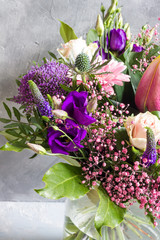 Purple and pink flowers bouquet. Glass vase. Gray backround.