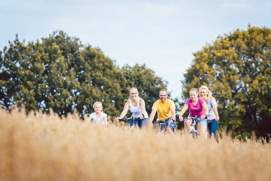 Family riding their bikes shot above a grain field in summer