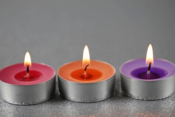 Drei farbenfrohe Teelichter auf silbernem Bokeh Hintergrund