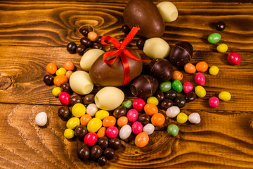Chocolate easter eggs and multicolored candies on wooden table