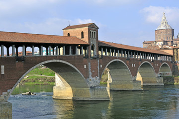 Fototapeta na wymiar Italy - Pavia - The Covered Bridge (also called Ponte Vecchio) on the ticino with the Cathedral of the city in the background