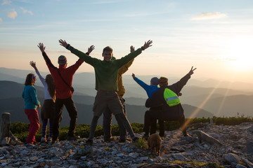 Happy hikers, friends with open arms are standing on a top