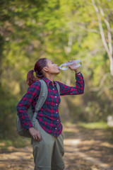 Happy woman tourist with backpack drinking water in nature.