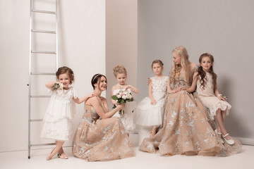 Little pretty girls with flowers dressed in wedding dresses