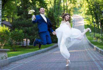 bride and groom jumping together holding hands