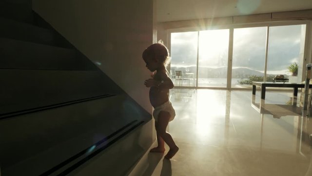 Little girl learning walk on spacious room in modern apartments