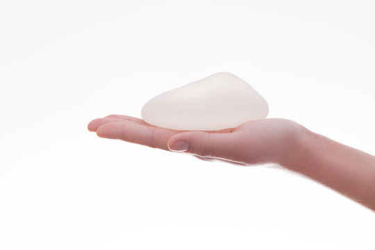 Silicone breast implant on hands .