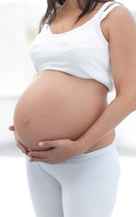 closeup of a pregnant woman putting her hands on her tummy.