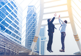 Happy successful two businessman jumping clap each other hand in the air. Two man happily jumping as a business achievement, achieve goal. Business conceptual.