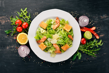 Caesar salad with chicken and fresh vegetables. On a wooden background. Top view. Copy space.