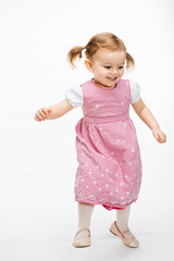 Full body portrait of a happy energetic toddler girl captured in movement, dancing girl with ponytails