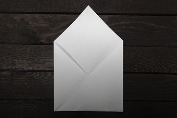 White opened envelope from above on wood. Gradient filter.
