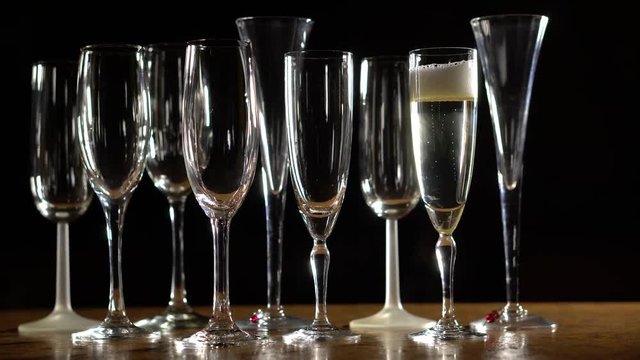 Pulling away from champagne glasses with one filled glass of bubbling liquid.
