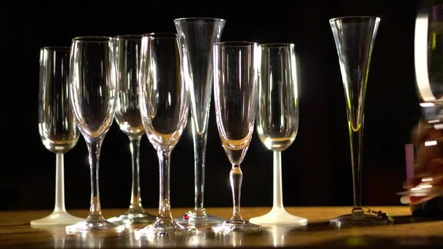 Sliding in on champagne glasses as one glass is put into place all against a black background.