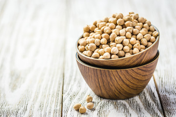 Chickpeas in bowls on wooden rustic background. Selective focus, space for text. 