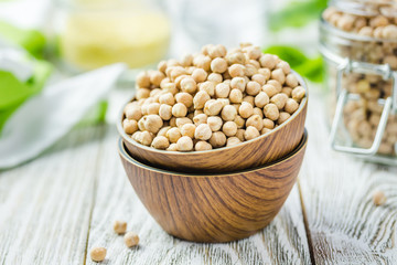Chickpeas in bowls on wooden rustic background. Selective focus, space for text. 