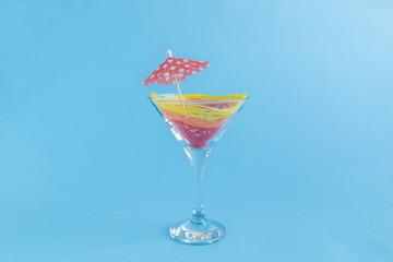 Sex on the beach cocktail formed from threads and red paper parasol in drinking glass. Summer alcohol drink minimalistic creative concept.