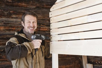 a carpenter with a screwdriver makes a wooden bed