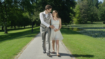 Fototapeta premium Happy young couple gaze at each other while gently stroking her pregnant belly