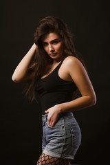 Model test with wonderful young model in black shirt and jeans shorts posing in the shadows