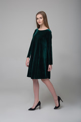 Naklejka premium Young beautiful long-haired female model in dark green short dress